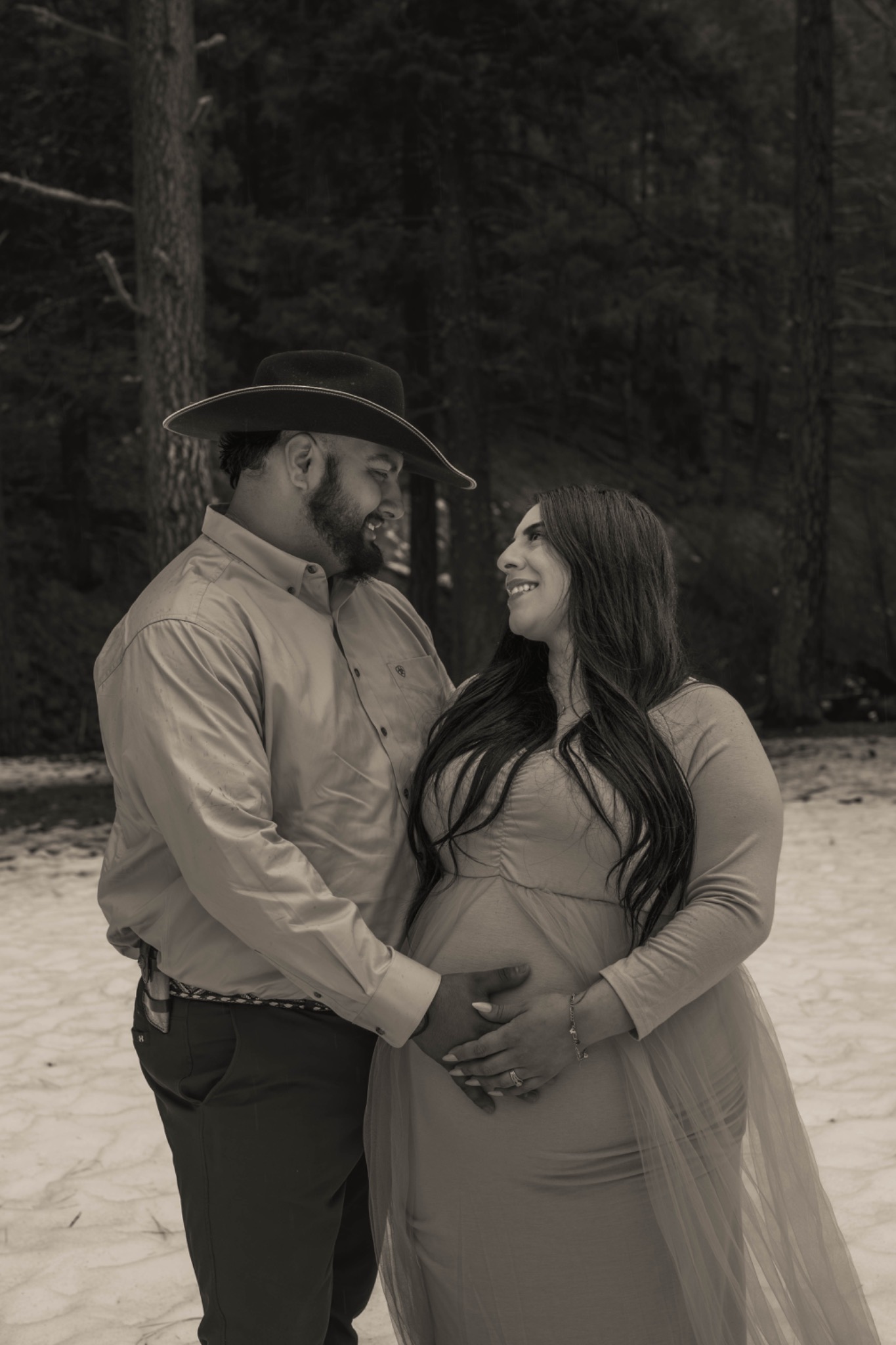 Black-and-white portrait of an expectant couple smiling at each other