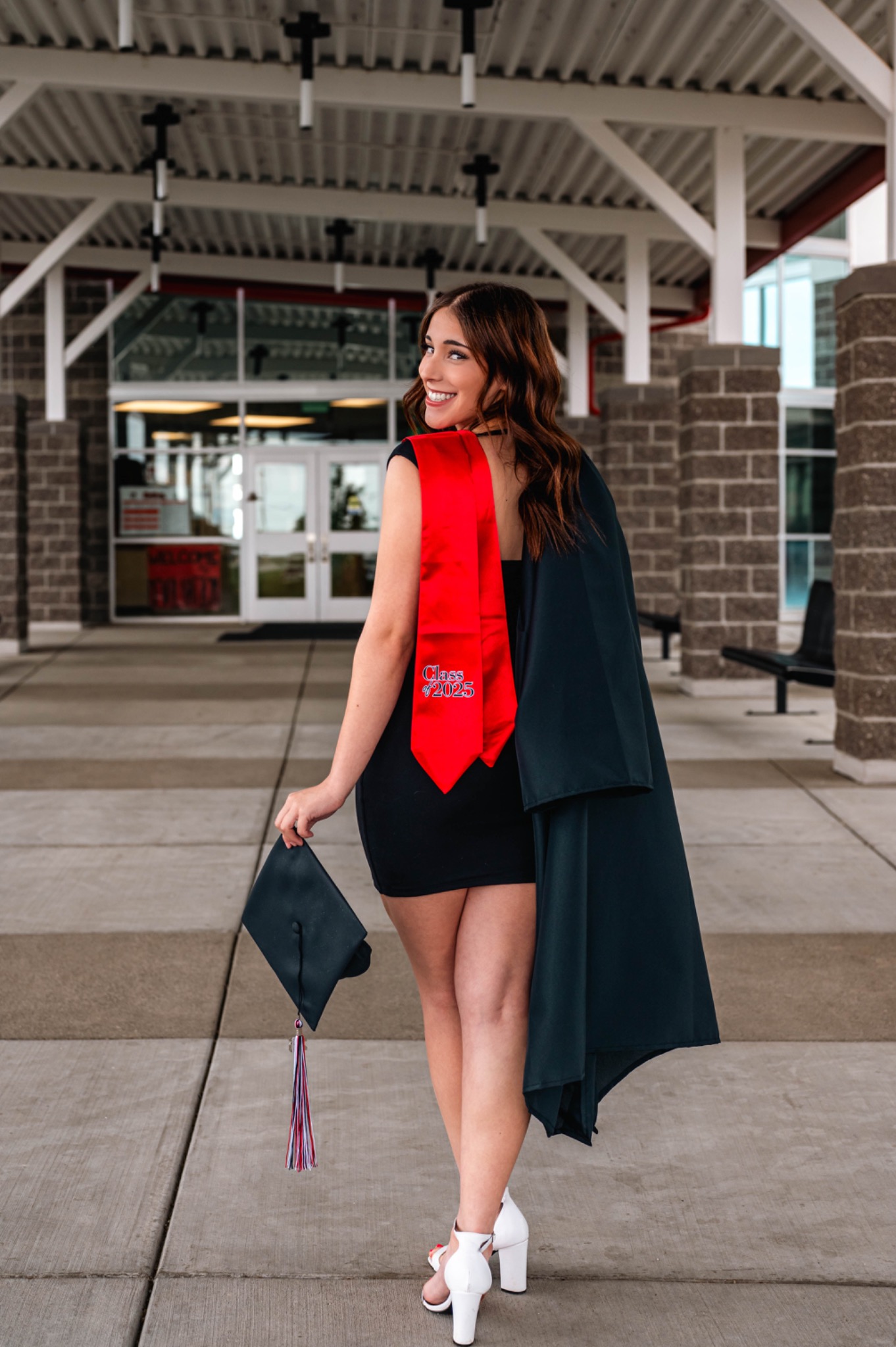 Graduate looking back with a smile while holding her cap